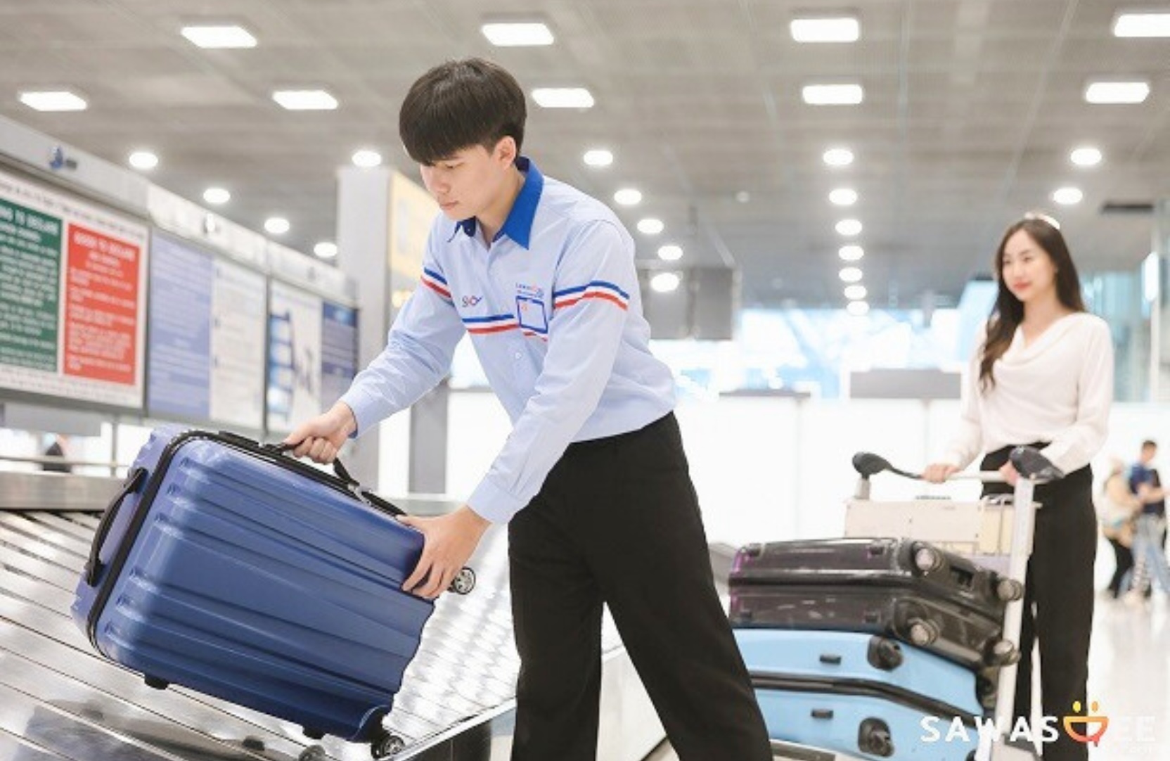 Airport porter collecting baggage from carousel